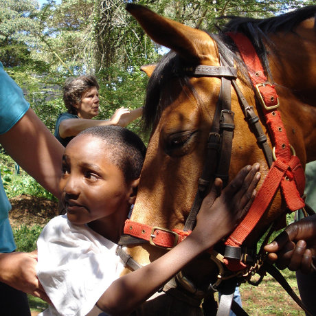 Child being helped into the saddle by volunteers